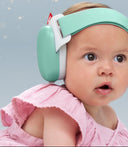 Baby wearing a mint green and white headband with a pink outfit against a light blue background