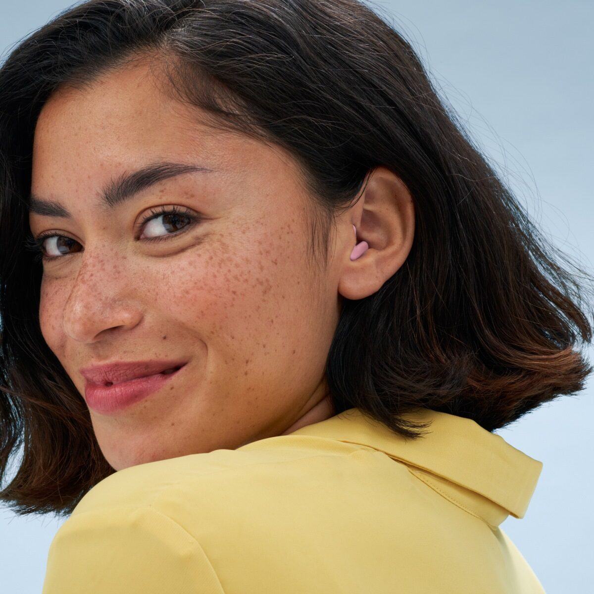 Een vrouw is blij terwijl ze Alpine Silence-oordoppen draagt.