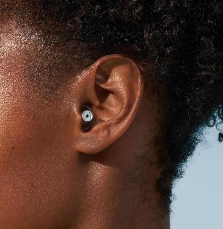 Close-up van het oor van een vrouw met Alpine-oordoppen.