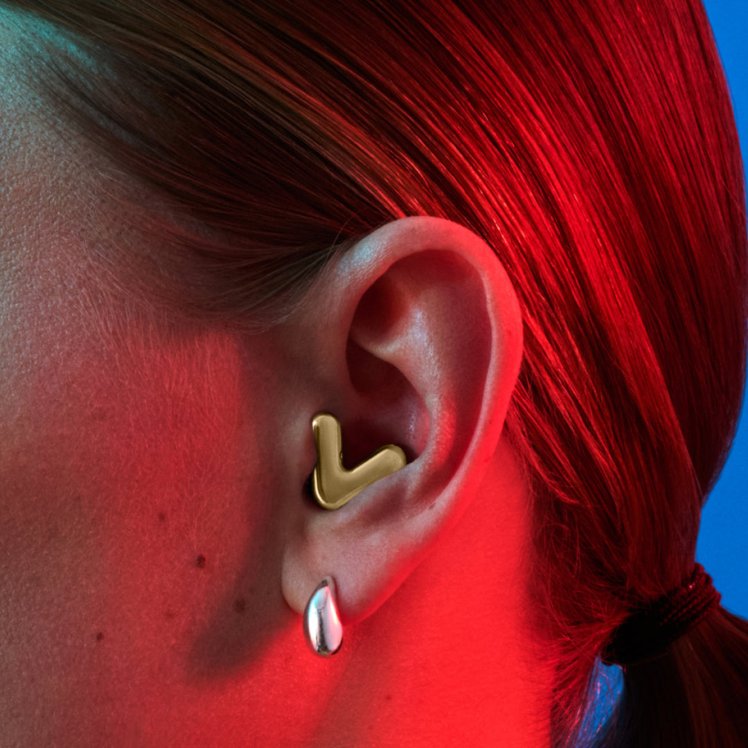 Detailed image of an ear with an Alpine Tune earplug in gold showing the snug fit in ear 